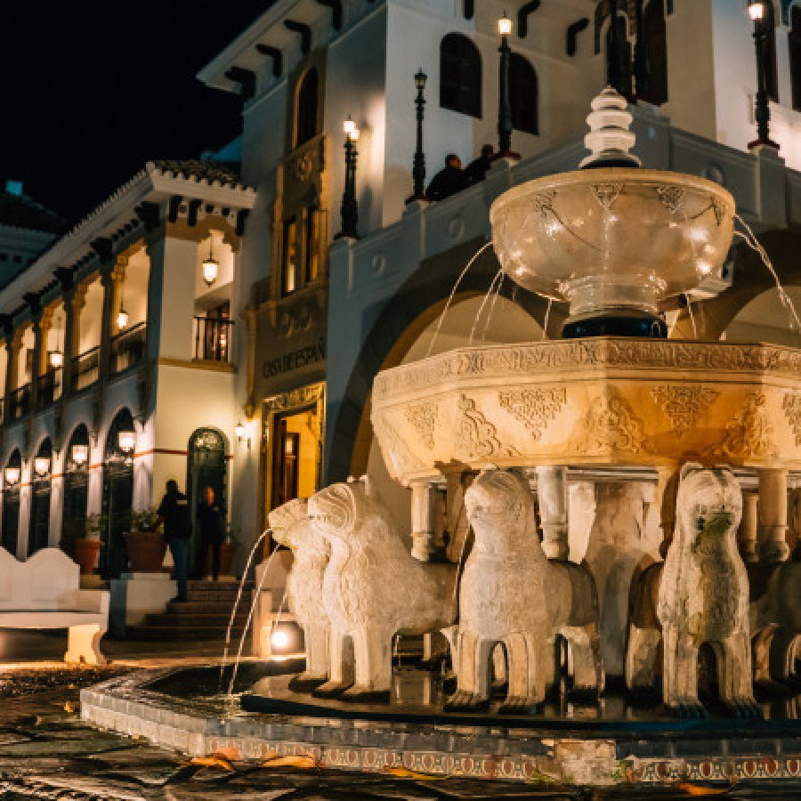 Exterior of the historic Casa de España, featuring an ornate fountain lined with lion sculptures.