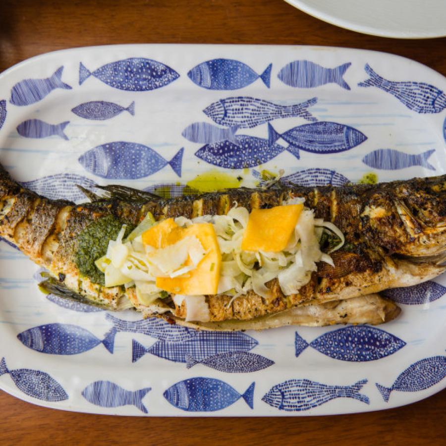 A cooked whole fish sits on a porcelain plate. 