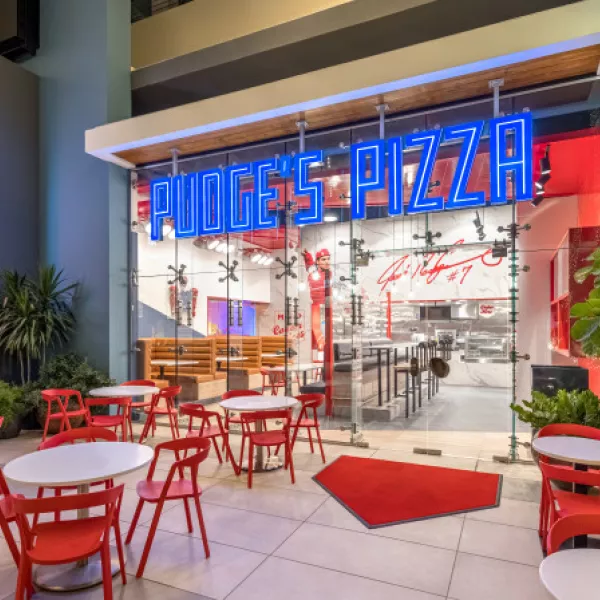 Colorful interior of Pudge’s Pizza at Distrito T-Mobile with red tables and vibrant décor.