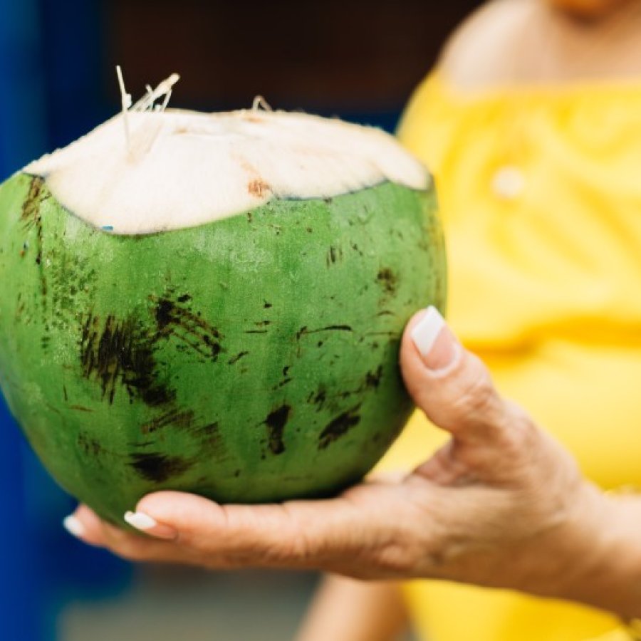 A woman holds a fresh coconut at the Kioskos de Luquillo