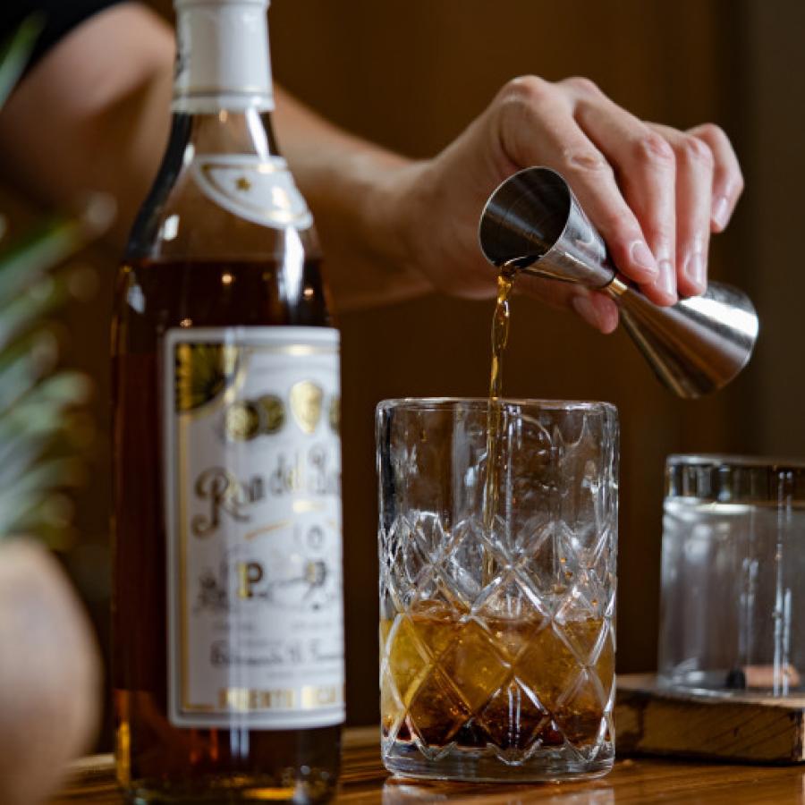 A bartender pours a shot of Ron del Barrilito into a glass