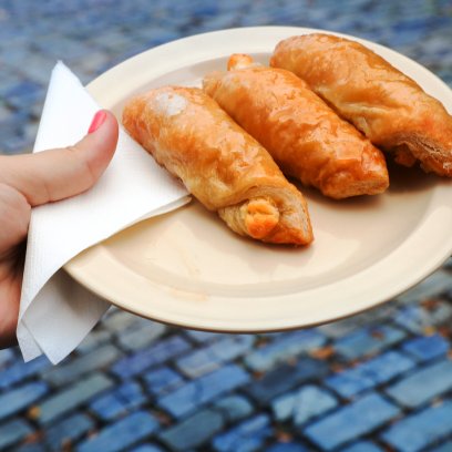A woman's hand holding a plate with quesitos, traditional Puerto Rican pastries.