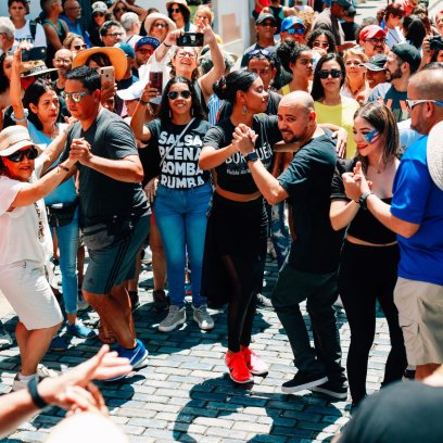 A joyful crowd participates in salsa dancing in the streets of historic Old San Juan, a lively display of Puerto Rican culture and community spirit.