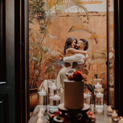 A couple embraces on a balcony at Hotel El Convento with a wedding cake in the foreground — a romantic venue for Puerto Rico wedding packages.