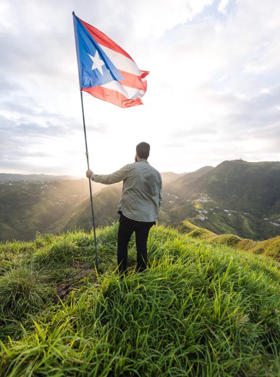 Majestic mountain view with man holding Puerto Rican flag. 