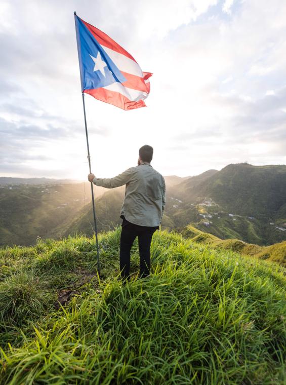 Majestic mountain view with man holding Puerto Rican flag.