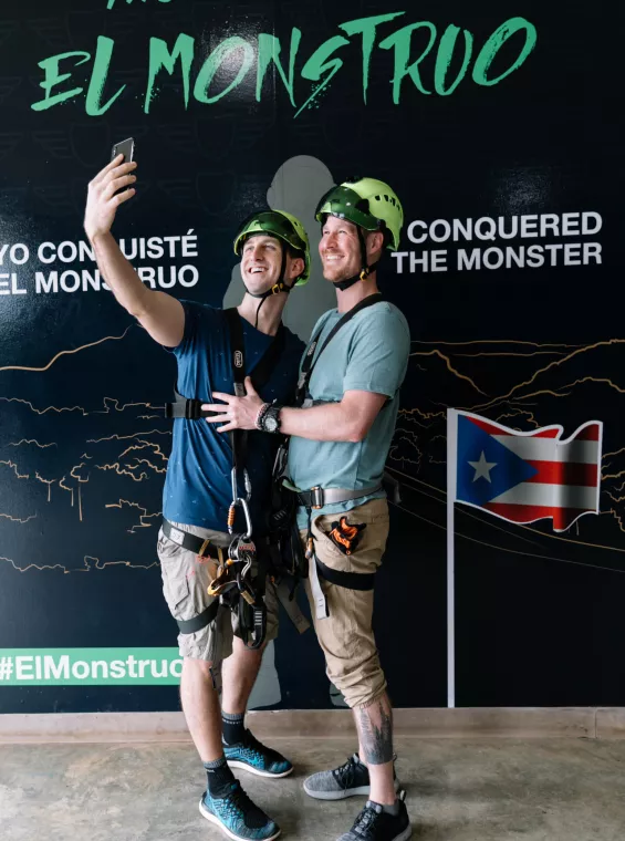 Two guys taking a selfie in front of "The Monster" sign at Toro Verde Zipline. 