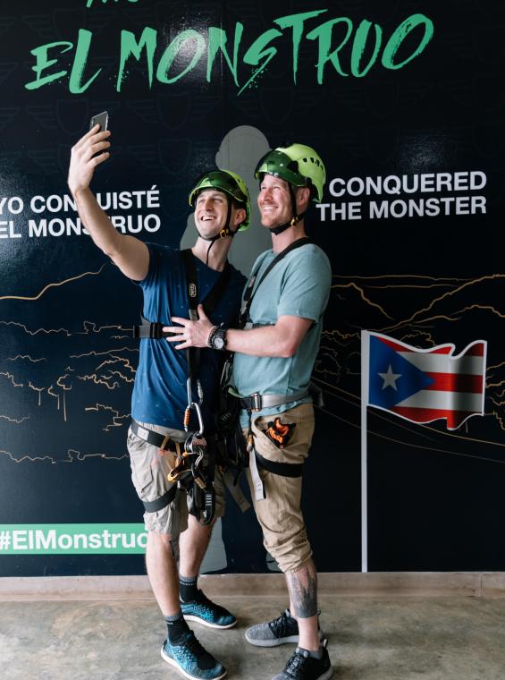 Two guys taking a selfie in front of "The Monster" sign at Toro Verde Zipline.