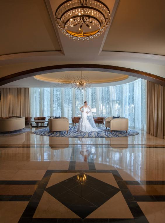 A woman in a wedding dress standing in an opulent hallway. 