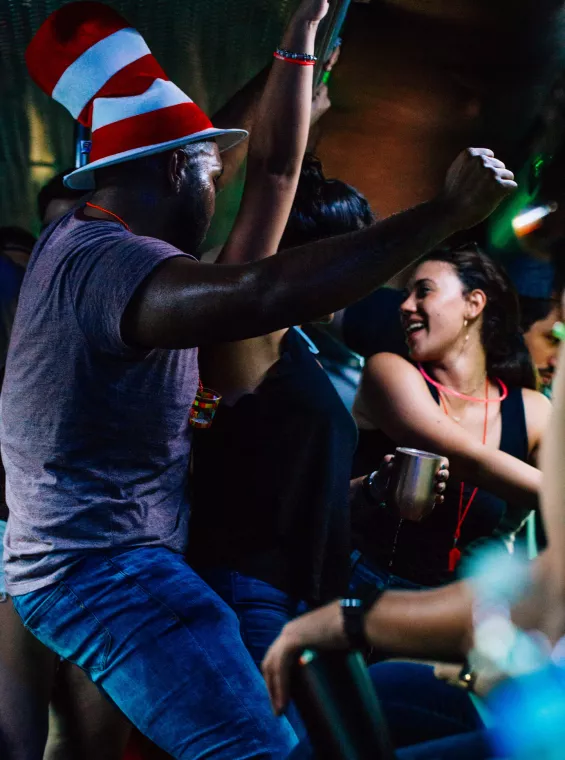 A man in a striped hat dancing in a group. 