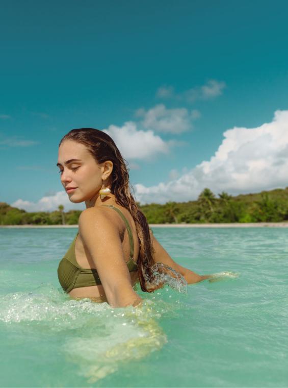 A woman wades through turquoise water on Playa Media Luna in Vieques, Puerto Rico