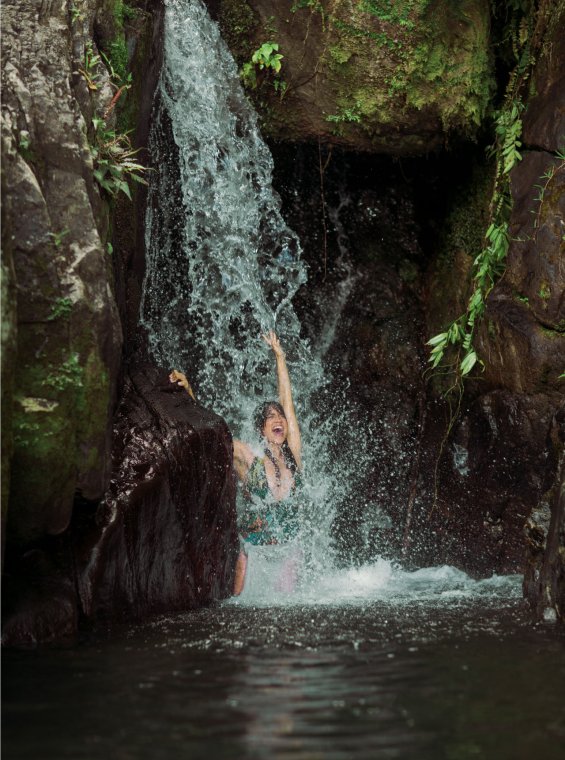 Una mujer juega bajo una cascada en Puerto Rico.