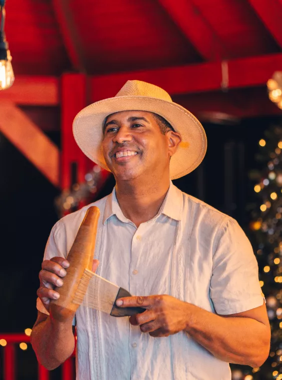 A person playing a güiro, a gourd shaped instrument