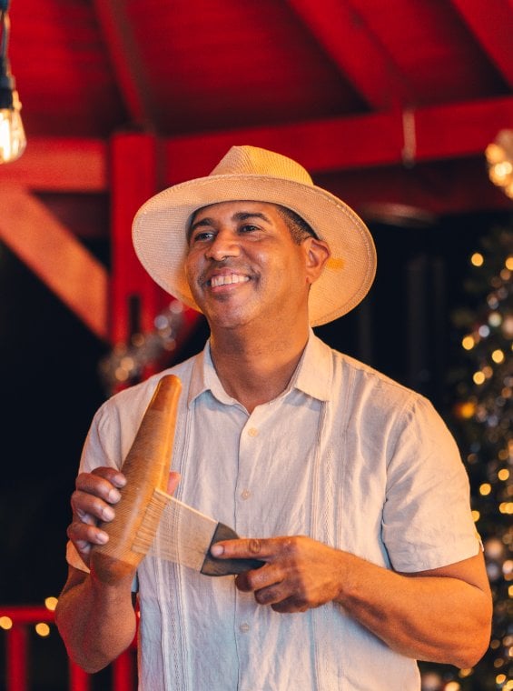 A person playing a güiro, a gourd shaped instrument