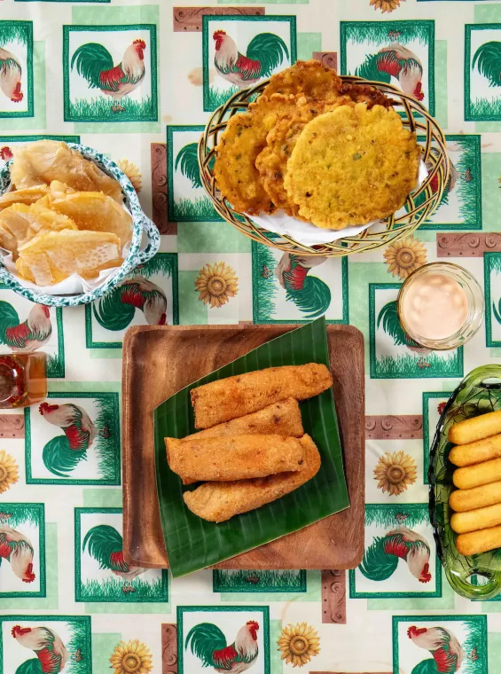 Traditional Puerto Rican fritters and snacks served on a table with a colorful patterned tablecloth.